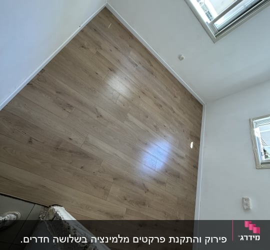 רצפת פרקט עץ בהירה בחדר ריק עם חלון פתוח